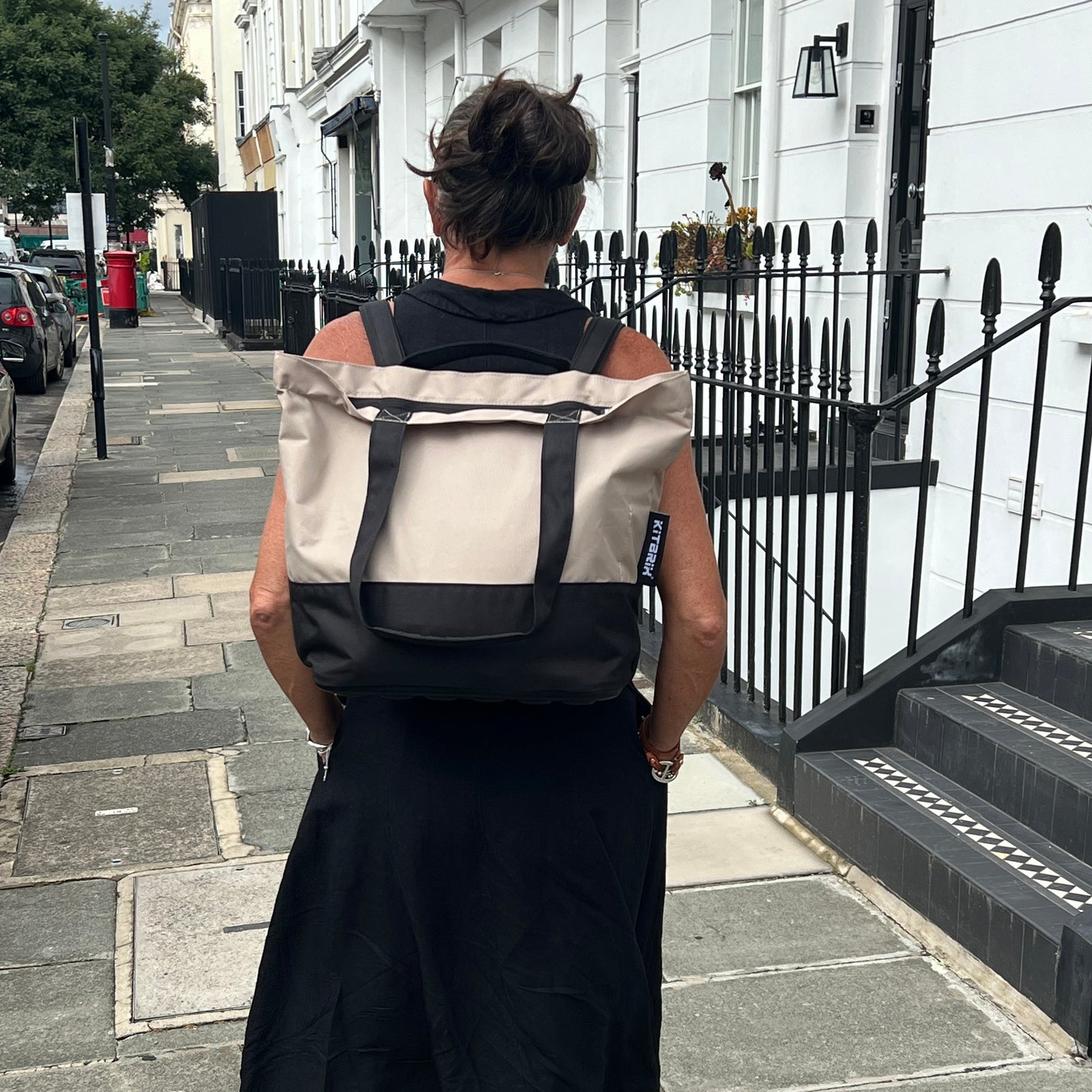 Person walking on a city street with a black and beige colour backpack