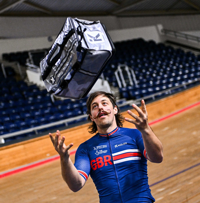 World Champion Track Cyclist Blaine Hunt, pictured at the velodrome, wearing blue Team GBR kit, throwing a Silver Kitbrix bag into the air.